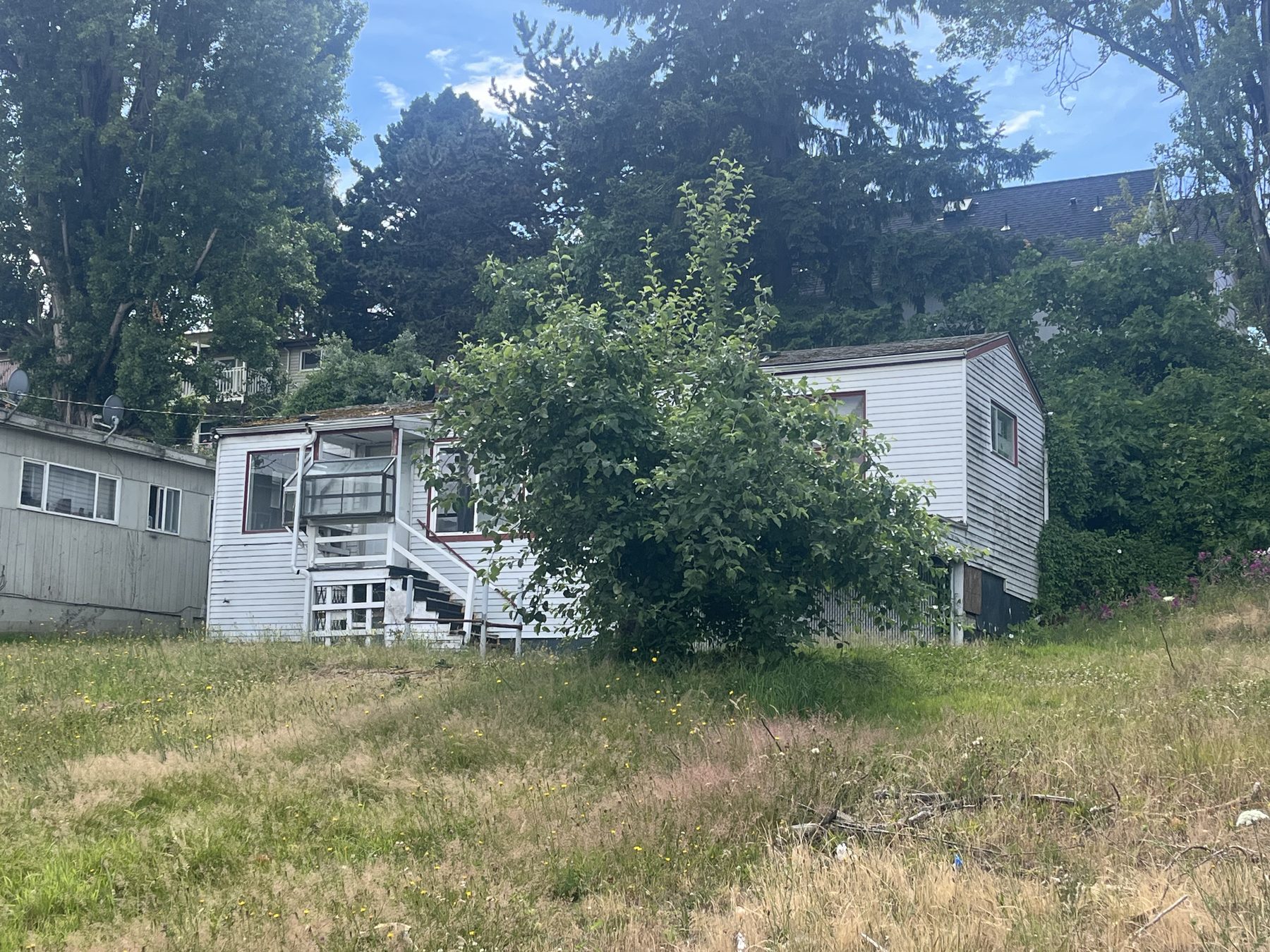 A run-down single-family house with an overgrown yard and peeling paint, the kind of distressed property that shows up in public records first