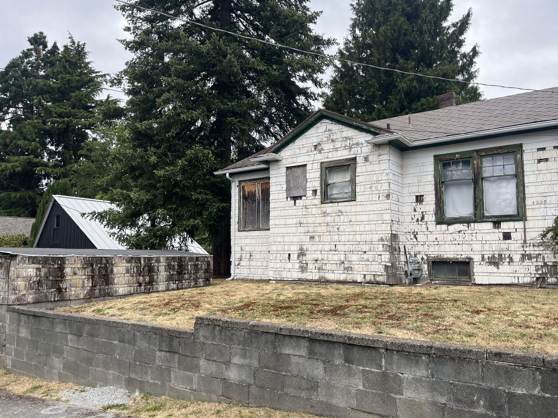 A boarded-up house with peeling paint and an overgrown lot, the kind of long-vacant property that surfaces in city code-violation records