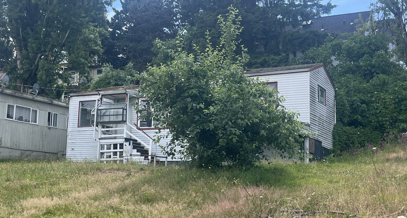 Boarded-up vacant home with an overgrown yard, the kind of distressed property that surfaces in public records before it ever lists on MLS.